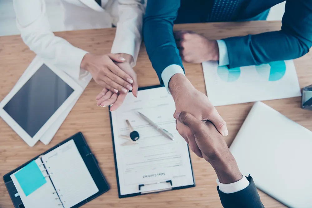 Above, top view of successful contract, owners of flat celebrate ownership, sitting in workplace, workstation, wearing suits, men shaking hands, woman congrats, applaud to them, it is successful deal